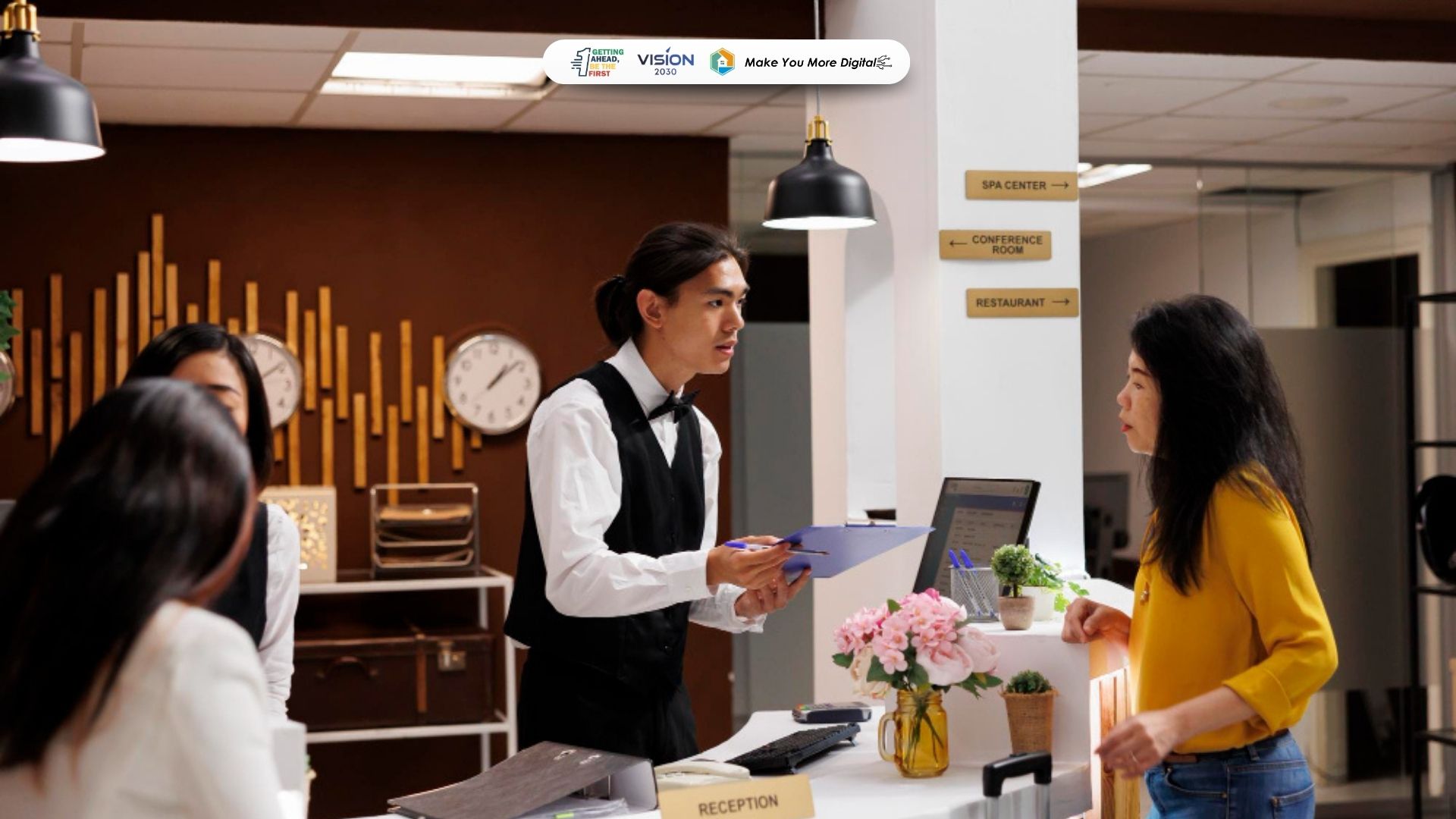 Petugas front office hotel sedang melayani tamu dengan profesional di meja resepsionis